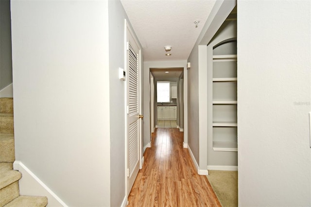 267 Goldenrain Dr Unit 30, Celebration, FL 34747 - hall with light wood-style flooring, stairway, a textured ceiling, and built in shelves