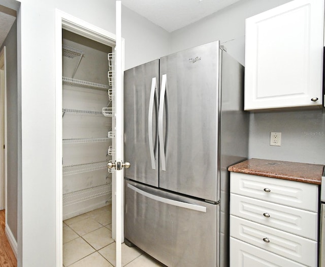 267 Goldenrain Dr Unit 30, Celebration, FL 34747 - kitchen with freestanding refrigerator, white cabinets, dark stone counters, and light tile patterned floors