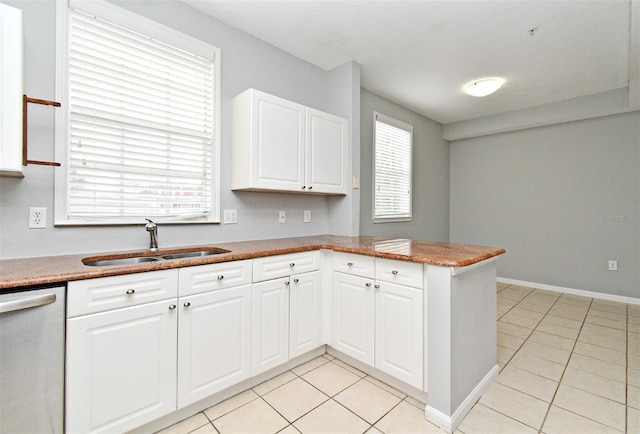 267 Goldenrain Dr Unit 30, Celebration, FL 34747 - kitchen featuring stainless steel dishwasher, a peninsula, light tile patterned floors, and white cabinetry