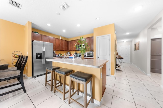 739 Jefferson, Davenport, FL 33837 - kitchen with stainless steel refrigerator with ice dispenser, light countertops, light tile patterned floors, a kitchen breakfast bar, and a kitchen island with sink