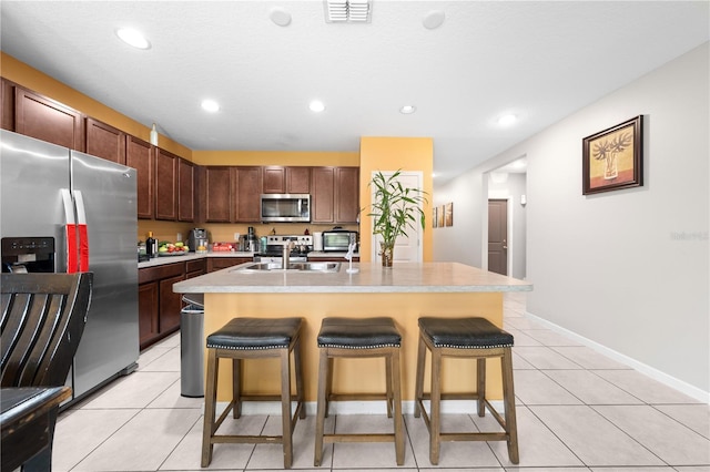 739 Jefferson, Davenport, FL 33837 - kitchen with stainless steel appliances, a kitchen breakfast bar, light countertops, light tile patterned floors, and a kitchen island with sink