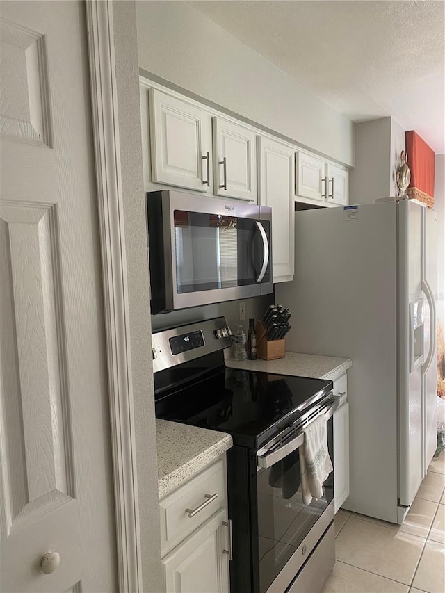 13327 Caspian Ln, Clermont, FL 34711 - kitchen featuring stainless steel appliances, light tile patterned flooring, white cabinets, and a textured ceiling