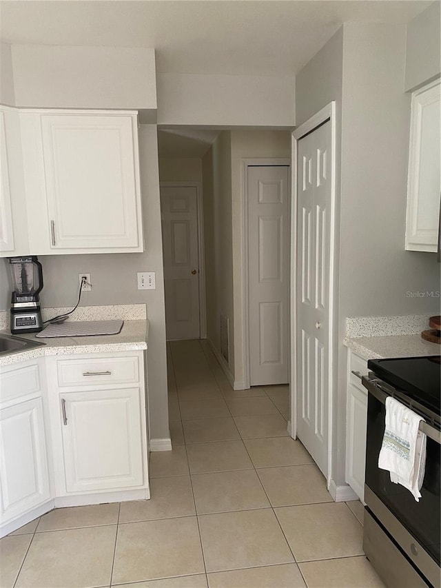 13327 Caspian Ln, Clermont, FL 34711 - kitchen with stainless steel range with electric cooktop, light tile patterned flooring, and white cabinets