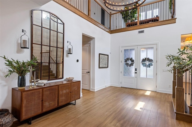 9352 Santorini Dr, Orlando, FL 32827 - foyer featuring french doors, a towering ceiling, a chandelier, and wood finished floors