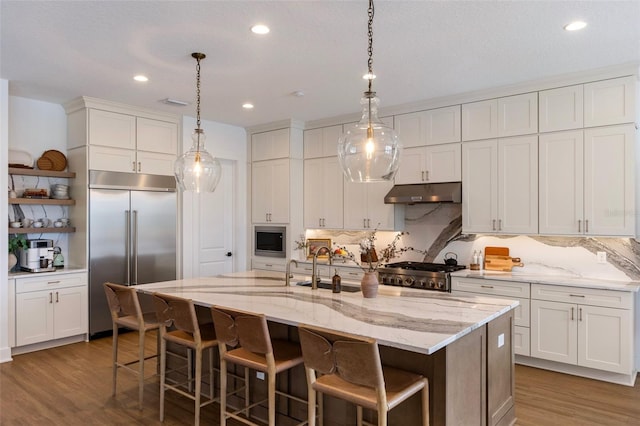 9352 Santorini Dr, Orlando, FL 32827 - kitchen featuring built in appliances, under cabinet range hood, decorative backsplash, wood finished floors, and white cabinets