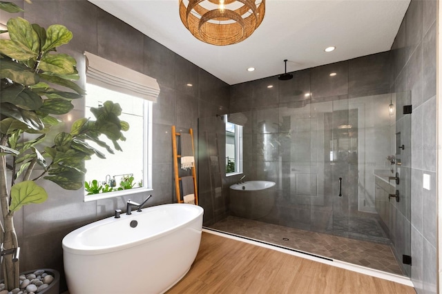 9352 Santorini Dr, Orlando, FL 32827 - bathroom featuring a shower stall, a soaking tub, wood finished floors, and tile walls