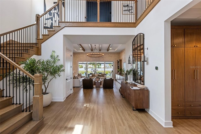9352 Santorini Dr, Orlando, FL 32827 - entrance foyer with light wood-style floors, stairs, a chandelier, a high ceiling, and beam ceiling