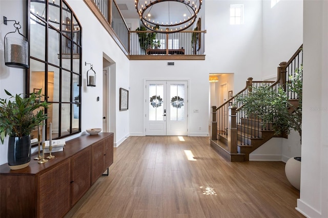 9352 Santorini Dr, Orlando, FL 32827 - entryway featuring french doors, stairway, a towering ceiling, wood finished floors, and a chandelier