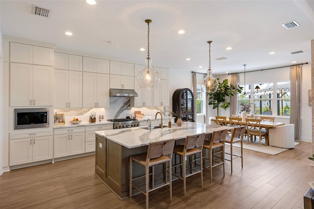 9352 Santorini Dr, Orlando, FL 32827 - kitchen featuring stainless steel microwave, light wood-style flooring, white cabinetry, and recessed lighting