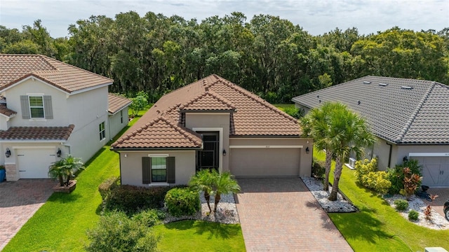 3837 Carrick Bend Dr, Kissimmee, FL 34746 - mediterranean / spanish house with decorative driveway, stucco siding, a tiled roof, an attached garage, and a front lawn