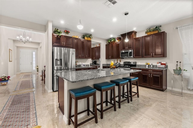 3837 Carrick Bend Dr, Kissimmee, FL 34746 - kitchen with appliances with stainless steel finishes, a kitchen bar, light marble finish floors, a chandelier, and a kitchen island with sink