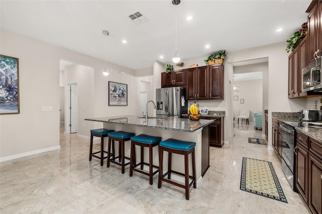 3837 Carrick Bend Dr, Kissimmee, FL 34746 - kitchen featuring appliances with stainless steel finishes, a kitchen breakfast bar, a kitchen island with sink, dark brown cabinetry, and recessed lighting