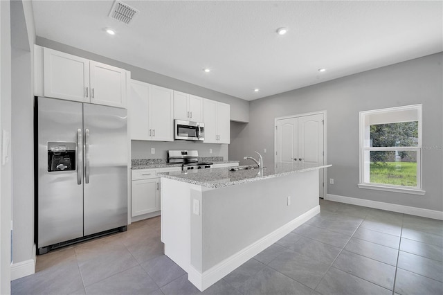 547 Viceroy Ct, Kissimmee, FL 34758 - kitchen featuring stainless steel appliances, an island with sink, white cabinetry, light stone counters, and light tile patterned floors
