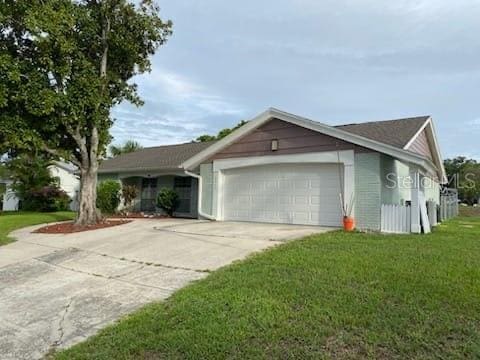 12215 Cobble Stone Dr, Hudson, FL 34667 - ranch-style house featuring an attached garage, driveway, and a front yard