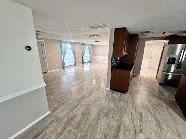 12215 Cobble Stone Dr, Hudson, FL 34667 - kitchen with stainless steel fridge with ice dispenser, open floor plan, dark brown cabinetry, dark countertops, and a textured ceiling