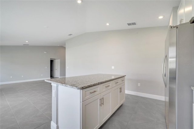 549 Viceroy Ct, Kissimmee, FL 34758 - kitchen with freestanding refrigerator, lofted ceiling, a kitchen island, light stone countertops, and white cabinetry