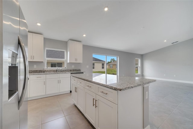 549 Viceroy Ct, Kissimmee, FL 34758 - kitchen featuring stainless steel fridge, a center island, white cabinetry, light stone counters, and light tile patterned flooring