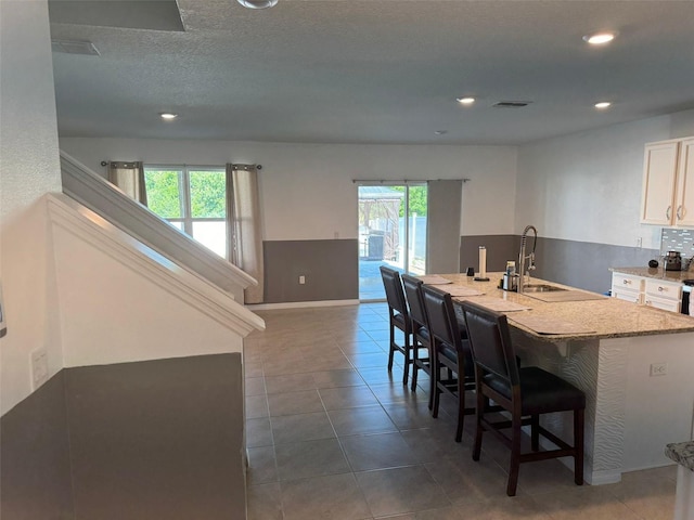 636 Autumn Stream Drive St, Auburndale, FL 33823 - kitchen with a breakfast bar area, white cabinetry, a center island with sink, recessed lighting, and dark tile patterned floors