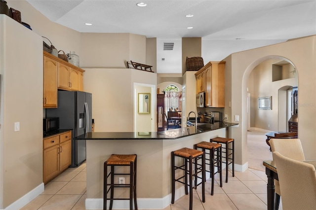 1525 Gants Cir, Kissimmee, FL 34744 - kitchen with black microwave, arched walkways, fridge with ice dispenser, a peninsula, and a kitchen bar