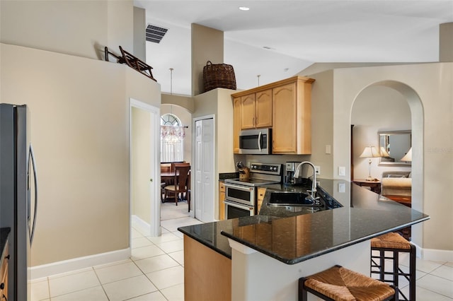 1525 Gants Cir, Kissimmee, FL 34744 - kitchen with appliances with stainless steel finishes, light tile patterned flooring, arched walkways, a kitchen breakfast bar, and a peninsula