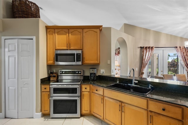1525 Gants Cir, Kissimmee, FL 34744 - kitchen with appliances with stainless steel finishes, dark stone countertops, light tile patterned floors, and french doors