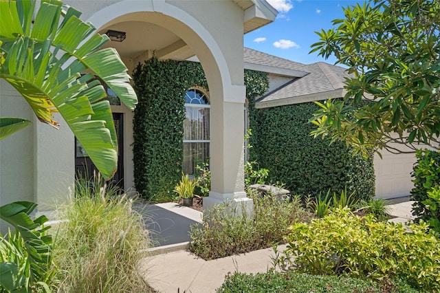 1525 Gants Cir, Kissimmee, FL 34744 - view of exterior entry featuring a shingled roof, stucco siding, and a garage