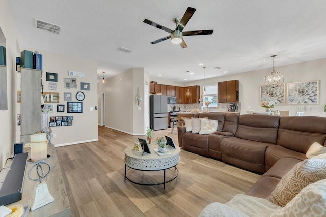 1864 Castleton Dr, Saint Cloud, FL 34771 - living area with a ceiling fan, light wood-style flooring, a chandelier, and a textured ceiling