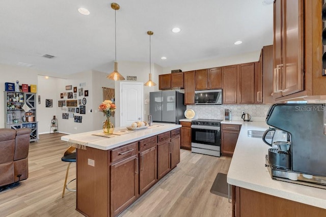 1864 Castleton Dr, Saint Cloud, FL 34771 - kitchen featuring stainless steel appliances, open floor plan, light wood finished floors, a kitchen bar, and light countertops