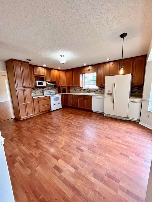 812 10th St, Saint Cloud, FL 34769 - kitchen with white appliances, light wood-type flooring, a textured ceiling, decorative backsplash, and brown cabinetry