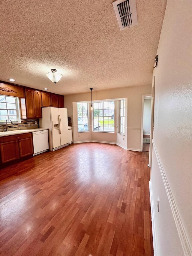 812 10th St, Saint Cloud, FL 34769 - kitchen with white appliances, a textured ceiling, wood finished floors, light countertops, and brown cabinets