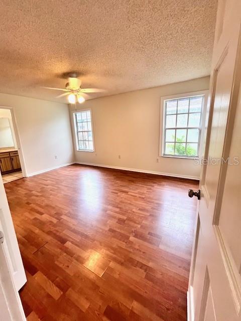 812 10th St, Saint Cloud, FL 34769 - empty room with wood finished floors, a textured ceiling, and a ceiling fan