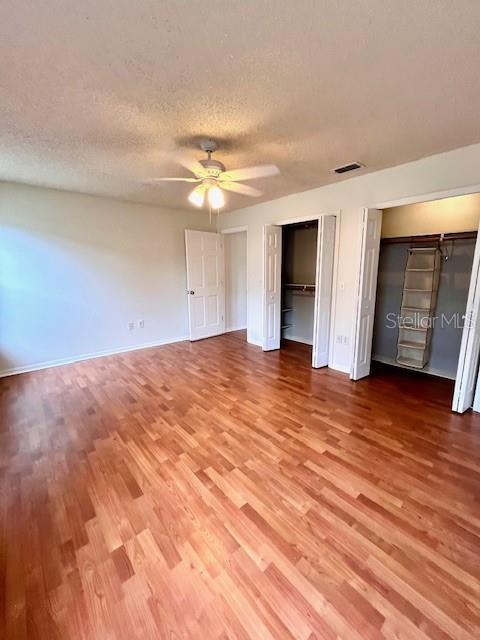 812 10th St, Saint Cloud, FL 34769 - unfurnished bedroom with wood finished floors, multiple closets, a textured ceiling, and ceiling fan