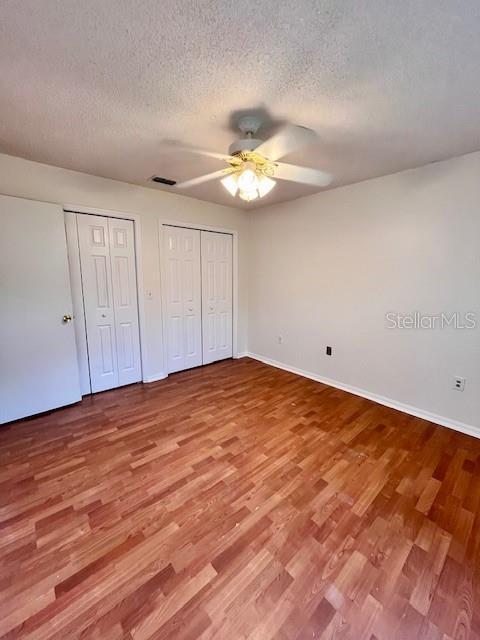 812 10th St, Saint Cloud, FL 34769 - unfurnished bedroom featuring multiple closets, wood finished floors, a textured ceiling, and ceiling fan