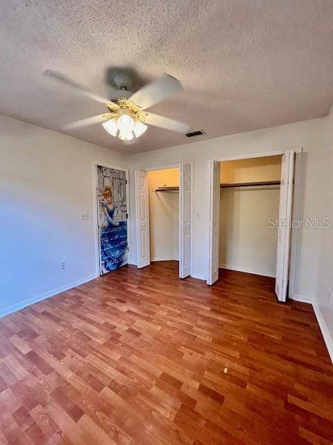 812 10th St, Saint Cloud, FL 34769 - unfurnished bedroom with a textured ceiling, wood finished floors, multiple closets, and ceiling fan