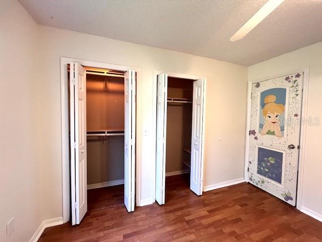 812 10th St, Saint Cloud, FL 34769 - unfurnished bedroom featuring dark wood-style floors and multiple closets
