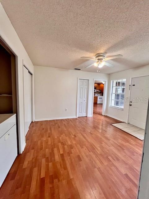 812 10th St, Saint Cloud, FL 34769 - unfurnished living room featuring light wood-style flooring, a ceiling fan, and a textured ceiling