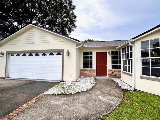 812 10th St, Saint Cloud, FL 34769 - ranch-style house featuring asphalt driveway, an attached garage, stucco siding, and brick siding