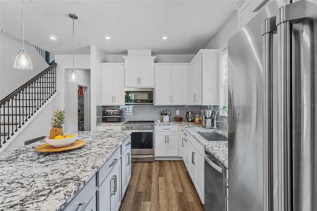 3252 Jackson Bluff Way, Clermont, FL 34711 - kitchen featuring stainless steel appliances, decorative backsplash, dark wood finished floors, white cabinets, and decorative light fixtures