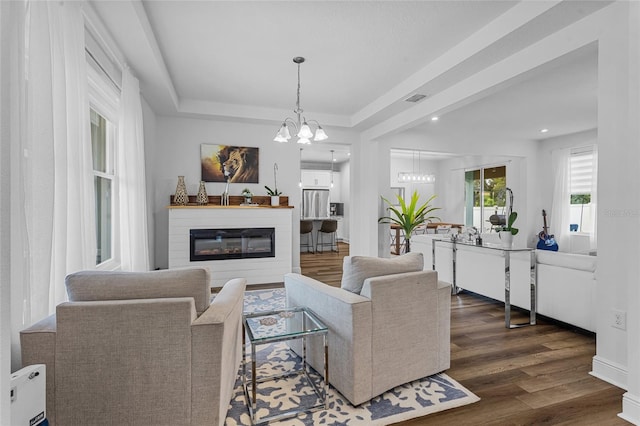 3252 Jackson Bluff Way, Clermont, FL 34711 - living room with dark wood finished floors, a chandelier, recessed lighting, a glass covered fireplace, and a raised ceiling