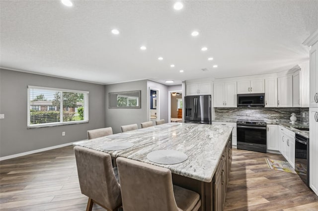 27805 Lois Dr, Tavares, FL 32778 - kitchen with stainless steel appliances, a center island, wood finished floors, recessed lighting, and light stone countertops