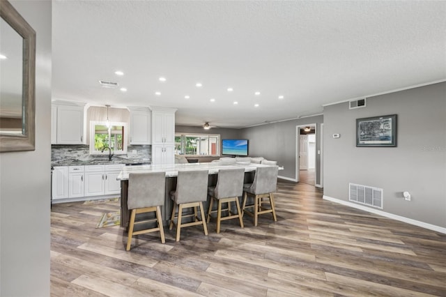 27805 Lois Dr, Tavares, FL 32778 - kitchen with a kitchen island, recessed lighting, white cabinetry, a breakfast bar, and wood finished floors
