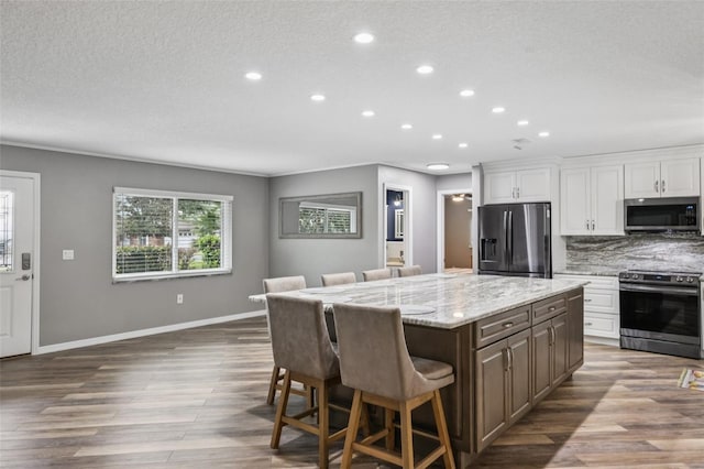 27805 Lois Dr, Tavares, FL 32778 - kitchen with stainless steel appliances, recessed lighting, a breakfast bar area, a center island, and white cabinets