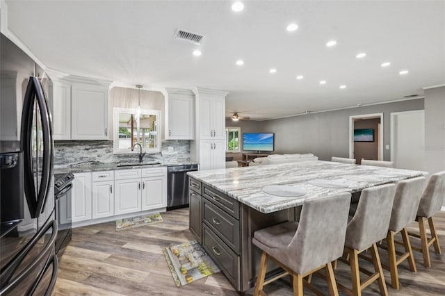 27805 Lois Dr, Tavares, FL 32778 - kitchen with appliances with stainless steel finishes, white cabinetry, a breakfast bar, open floor plan, and recessed lighting