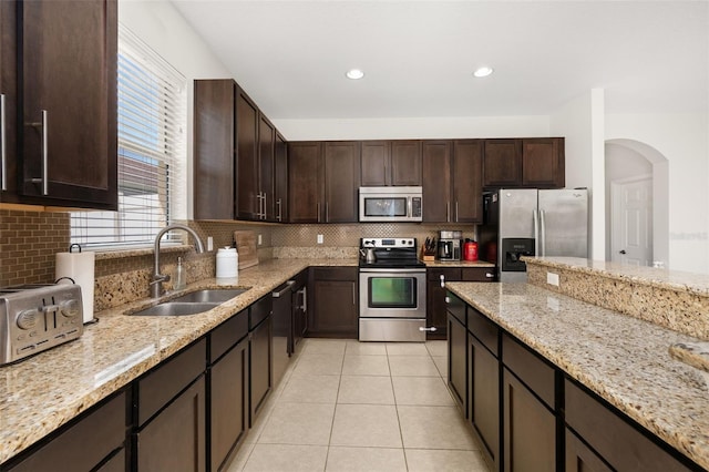 2823 Sail Breeze Way, Kissimmee, FL 34744 - kitchen featuring stainless steel appliances, dark brown cabinets, tasteful backsplash, light stone counters, and recessed lighting
