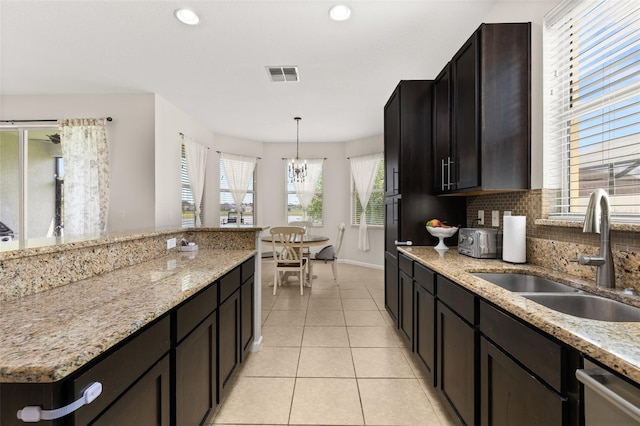 2823 Sail Breeze Way, Kissimmee, FL 34744 - kitchen featuring light tile patterned floors, a chandelier, stainless steel dishwasher, decorative backsplash, and pendant lighting