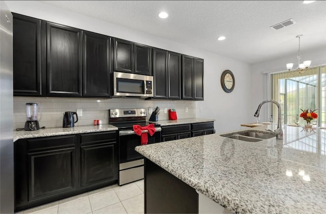 2231 Crofton Springs Ct, Davenport, FL 33837 - kitchen with appliances with stainless steel finishes, dark cabinetry, tasteful backsplash, a chandelier, and a textured ceiling