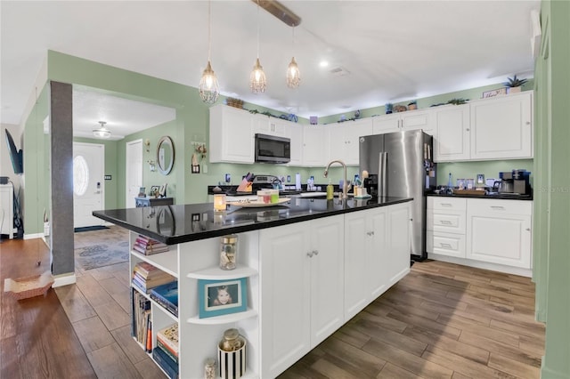 1203 Monterey Dr, Eustis, FL 32726 - kitchen featuring appliances with stainless steel finishes, open shelves, wood finished floors, white cabinetry, and dark countertops