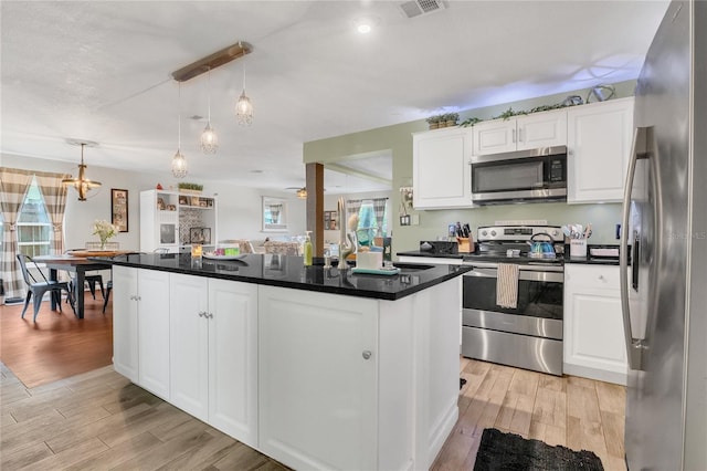 1203 Monterey Dr, Eustis, FL 32726 - kitchen featuring stainless steel appliances, light wood-type flooring, white cabinetry, dark countertops, and decorative light fixtures
