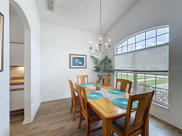 344 Bloomingdale Dr, Davenport, FL 33897 - dining area featuring plenty of natural light, arched walkways, wood finished floors, a chandelier, and vaulted ceiling