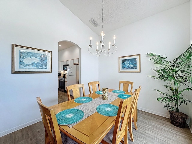 344 Bloomingdale Dr, Davenport, FL 33897 - dining area with arched walkways, light wood-type flooring, a chandelier, and high vaulted ceiling